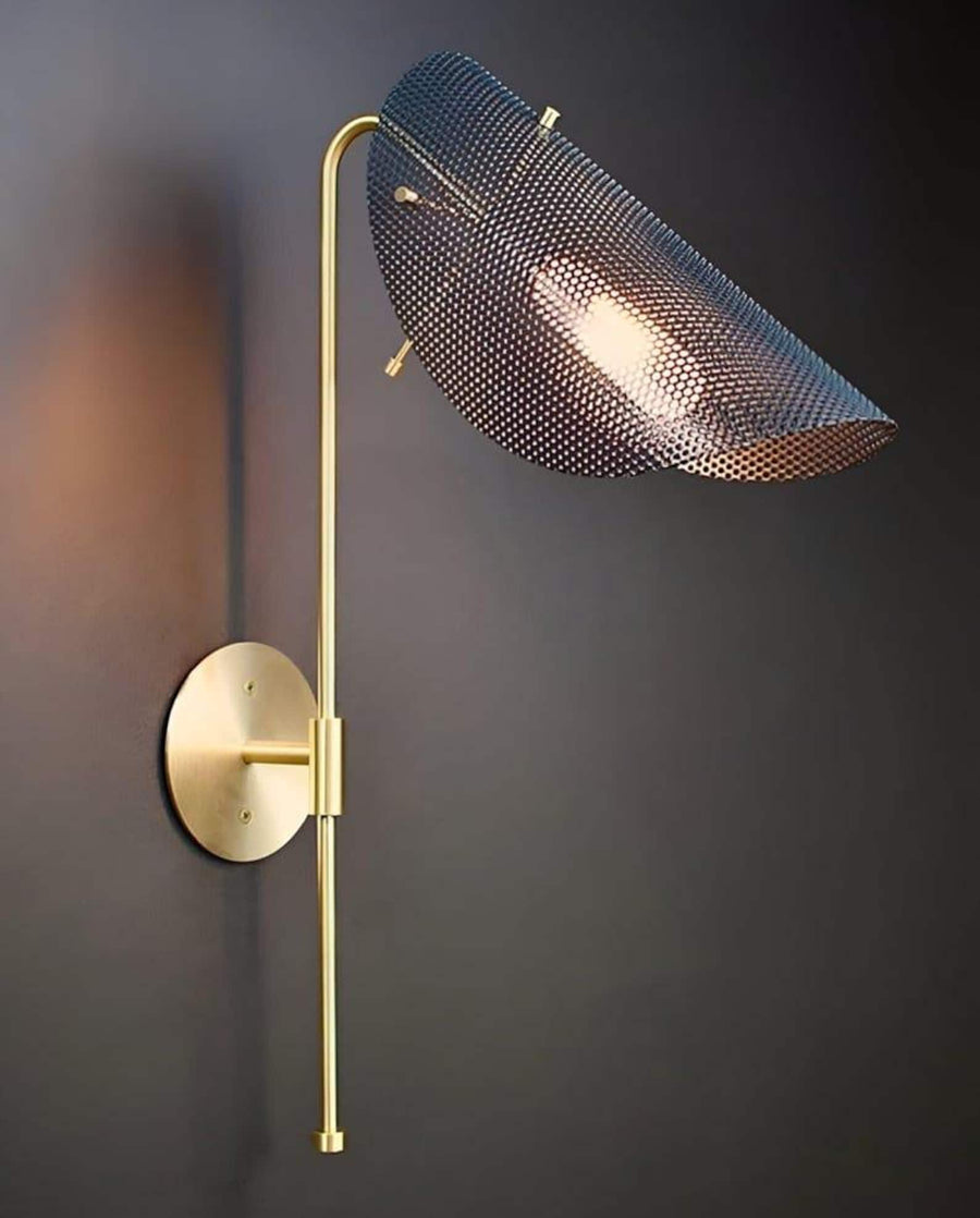 Curved brass wall lamp with perforated metal shade casting warm ambient light in a modern interior