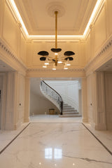 Curved shade brass statement chandelier with black upper shades, white cone lights, and warm multi-directional illumination