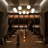 Custom brushed brass globe chandelier with nine lights, radial arms, and soft ambient glass globe illumination