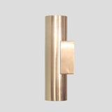 Polished brass cylindrical wall sconce with hidden slit glow, handmade for elegant modern and industrial-inspired spaces.