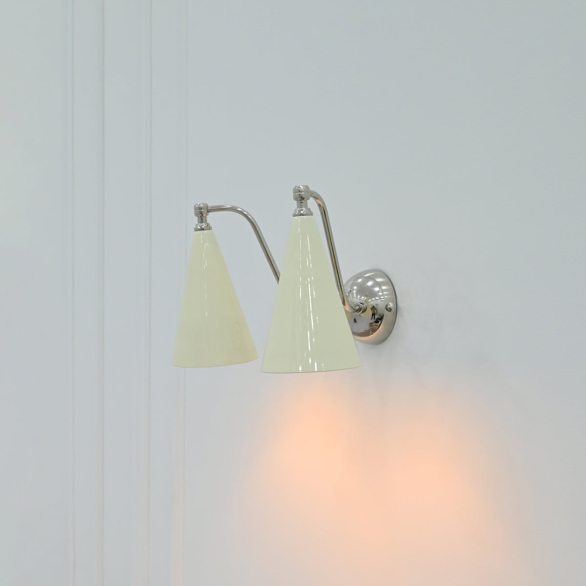 Ivory enamel wall sconce with two tapered shades and polished chrome mounting details