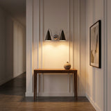 Statement double wall sconce with two ivory cone shades, curved chrome arms and warm focused lighting