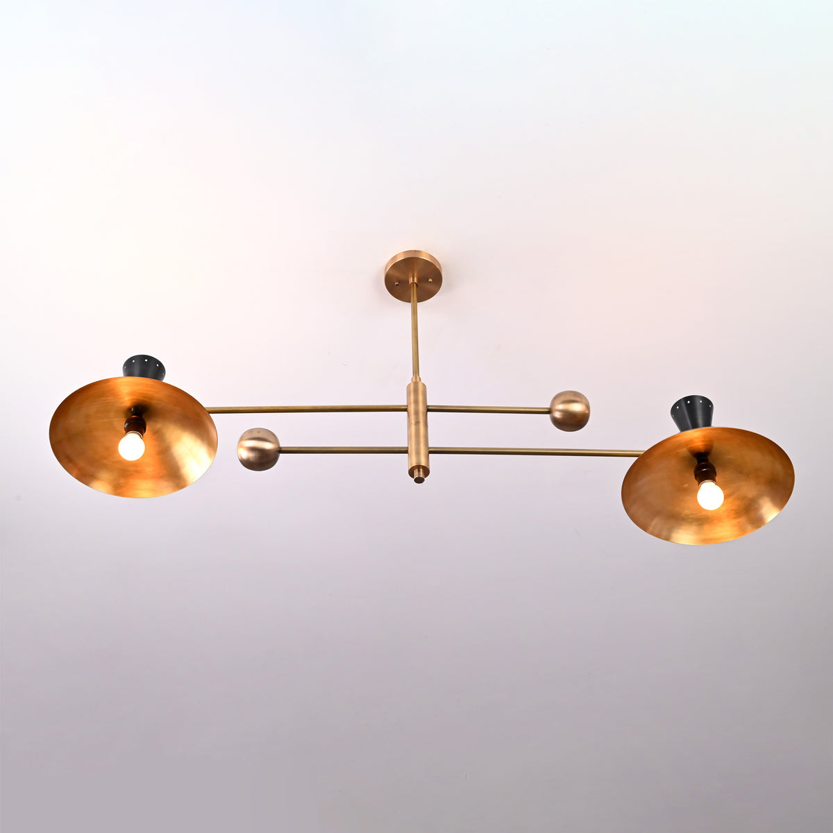 Top view of Diabolo 4-light brass chandelier featuring wide spun-brass bowl shades and black cone accents in a mid-century modern design.