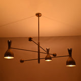 Close-up of Diabolo brushed brass chandelier showcasing perforated bowl shades and warm light diffusion.