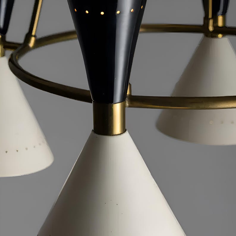 Detail view of Diabolo chandelier showcasing perforated cone shade, brass ring frame, and warm interior glow