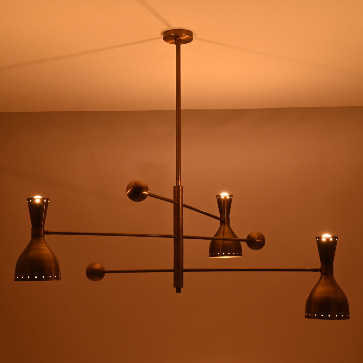 Mid-century inspired Diabolo brass chandelier casting an uplifting ceiling glow with elegant indirect lighting.