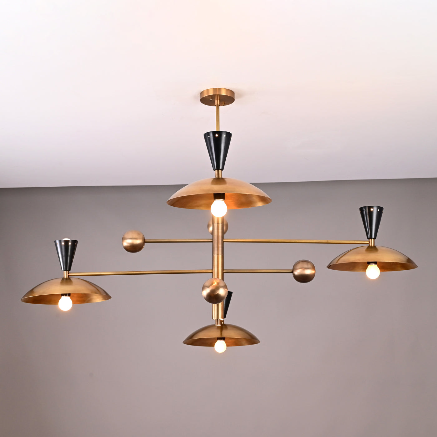 Front view of 8-light Diabolo chandelier crafted in brushed brass with sculpted bowl shades and black conical holders.