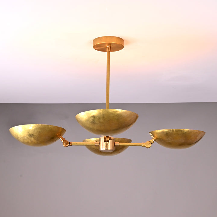 Brass chandelier with 4 upward bowls above dining table, creating a warm, elegant dining mood