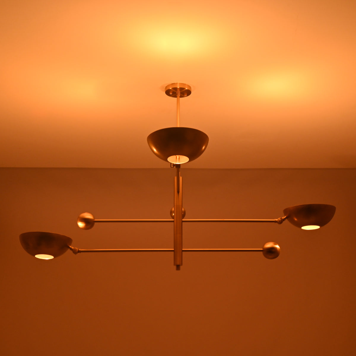 Disc style brass chandelier illuminated with warm ambient indirect lighting