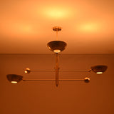 Disc style brass chandelier illuminated with warm ambient indirect lighting