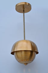 Angled view of brass dome pendant showing brushed brass finish and perforated base