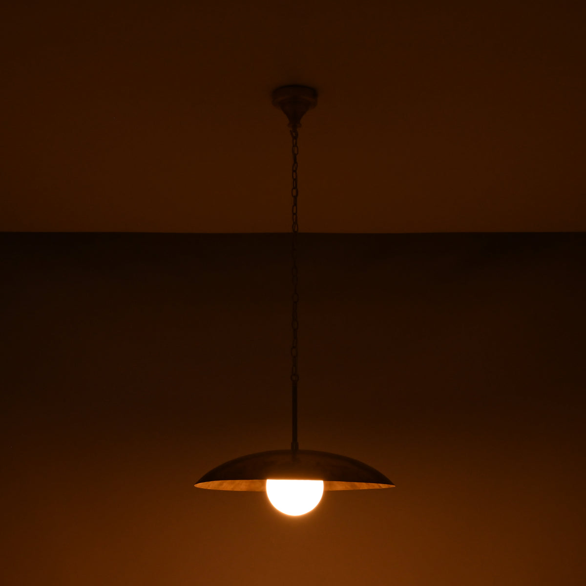 Dome disc pendant light with 20 inch shade and glowing 6 inch glass globe on dark background