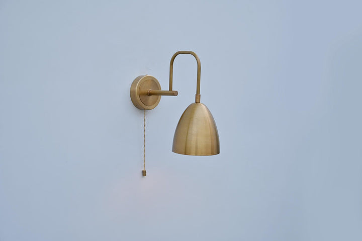 Dome-shaped brass wall light with minimal silhouette and pull chain, handcrafted in India by Brass Leaf Studio.
