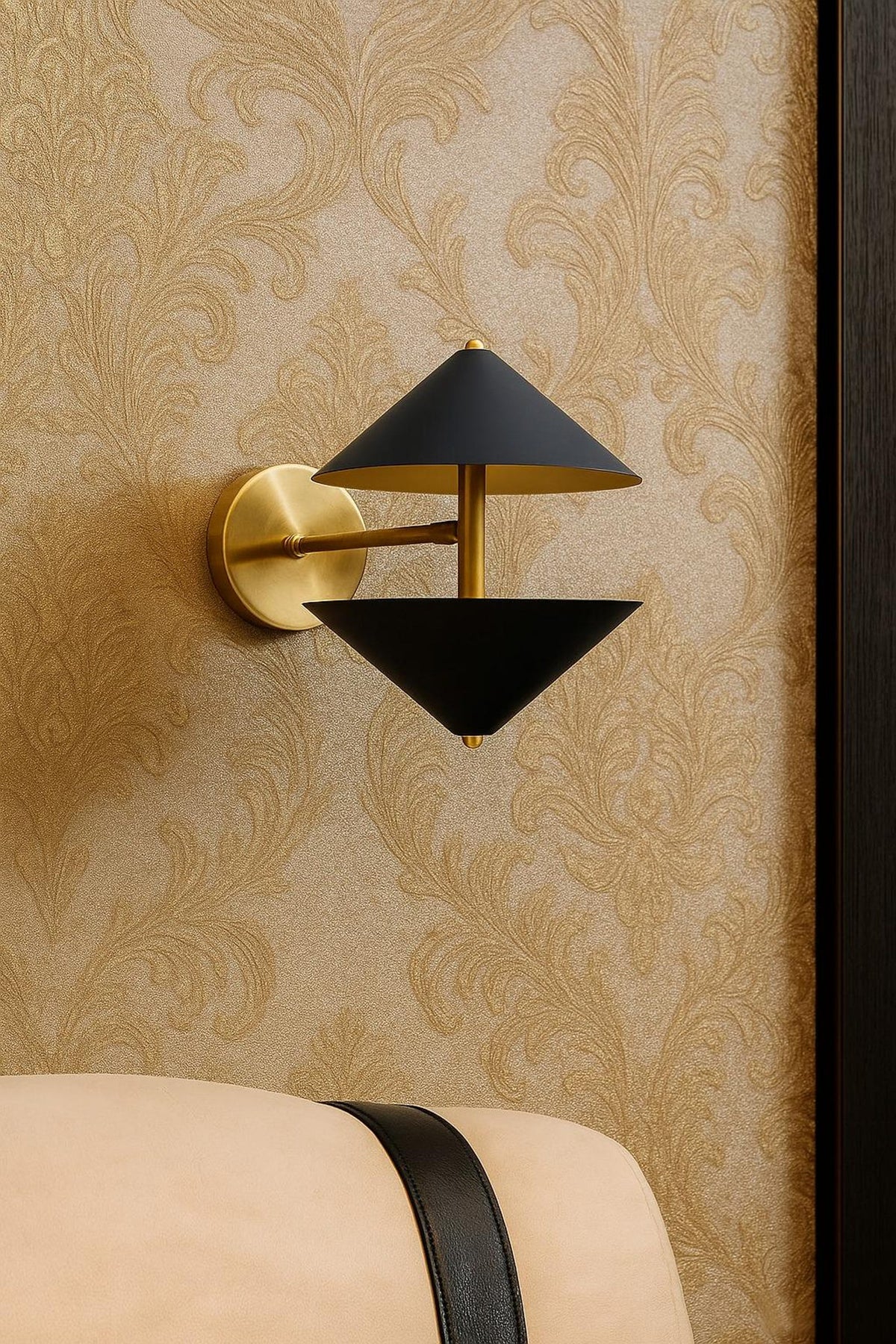 Modern double cone brass wall sconce installed beside bed with textured wallpaper background, elegant luxury bedroom lighting fixture.
