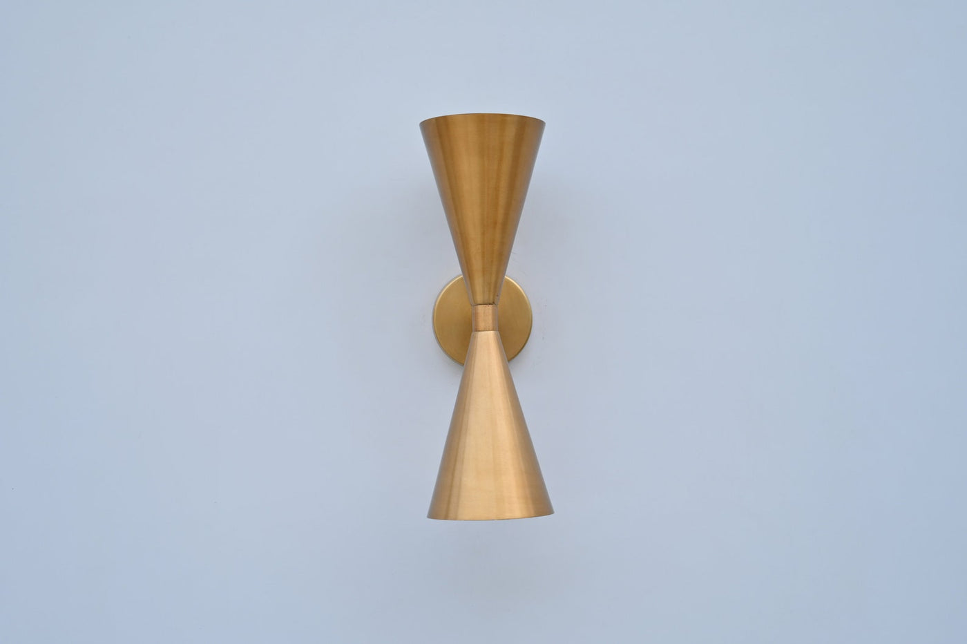 Front view of double cone wall light in brushed brass finish, handcrafted solid brass sconce with symmetrical up-and-down design.