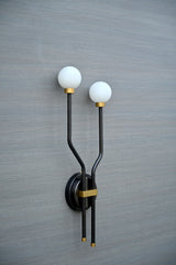 Angled close-up of handcrafted double globe wall sconce with brass accents and frosted globes