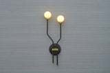 Front view of double globe brass wall sconce with minimalist black frame and frosted globes