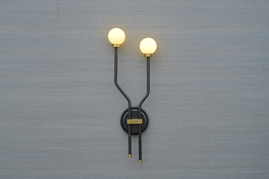 Front view of double globe brass wall sconce with minimalist black frame and frosted globes