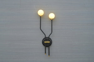 Front view of double globe brass wall sconce with minimalist black frame and frosted globes
