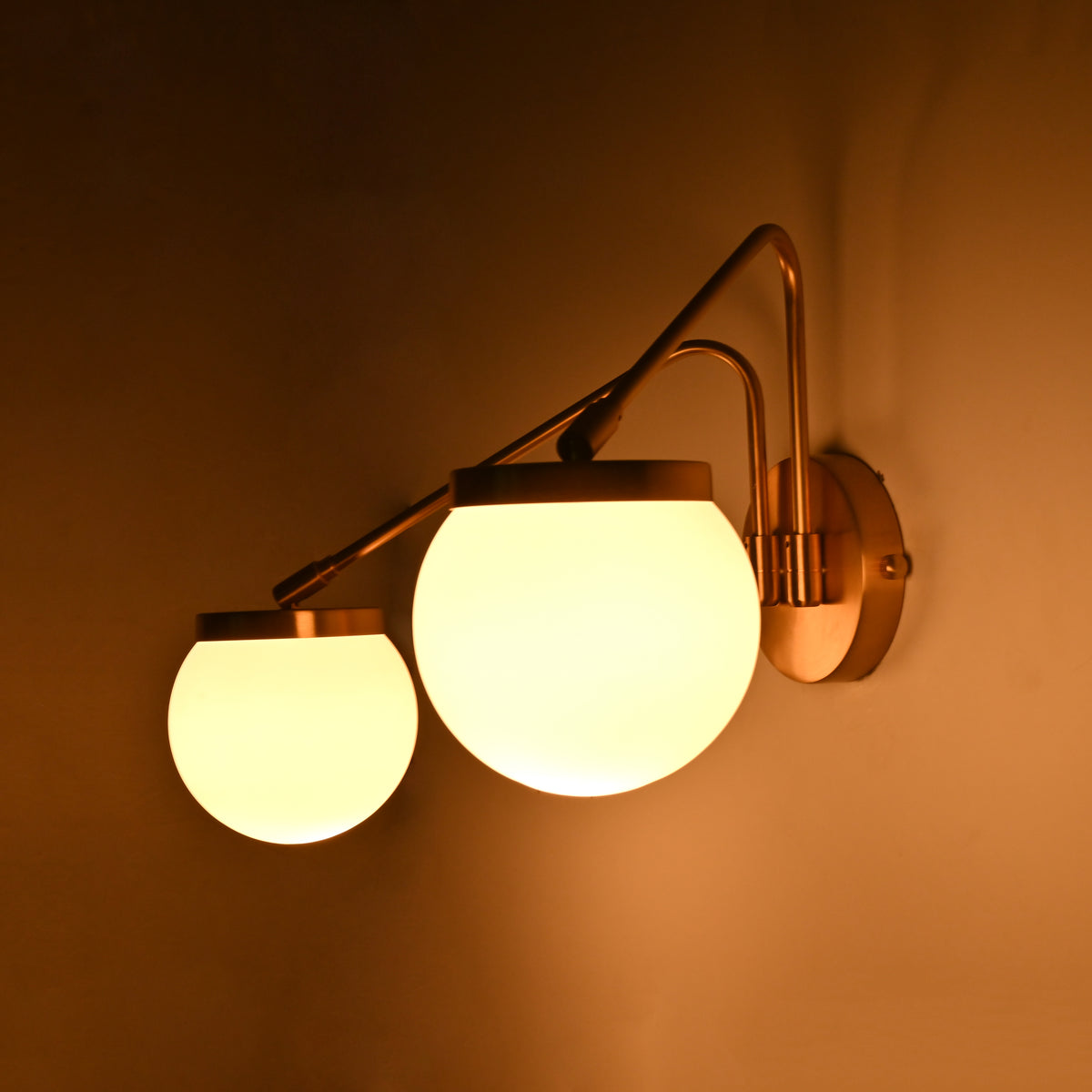 Double globe wall light shown illuminated, creating a warm glow for cozy bedrooms, hallways, and lounge spaces
