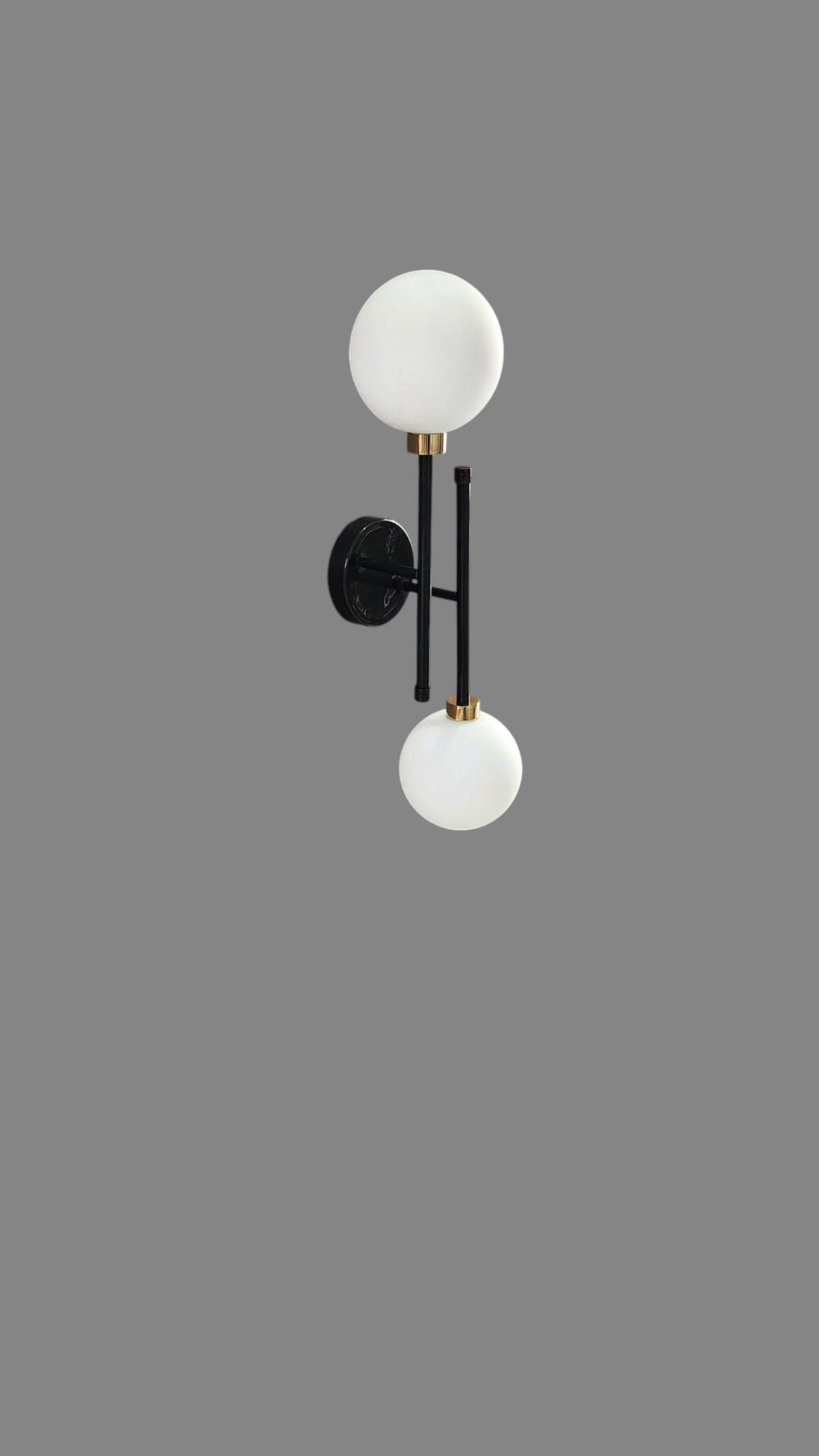 Side angle of dual globe wall sconce in black and brass with round wall plate and soft matte finish.