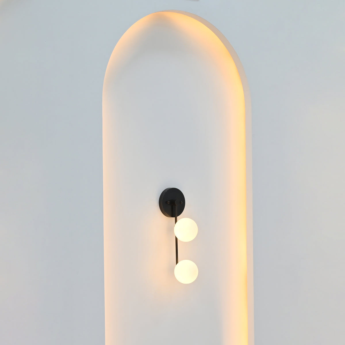 Two-light globe wall sconce illuminated with soft warm ambient light for bedroom, hallway, vanity, or living room interiors
