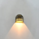 Compact dome wall light with dual patina brass surface creating a warm cone of light on the wall
