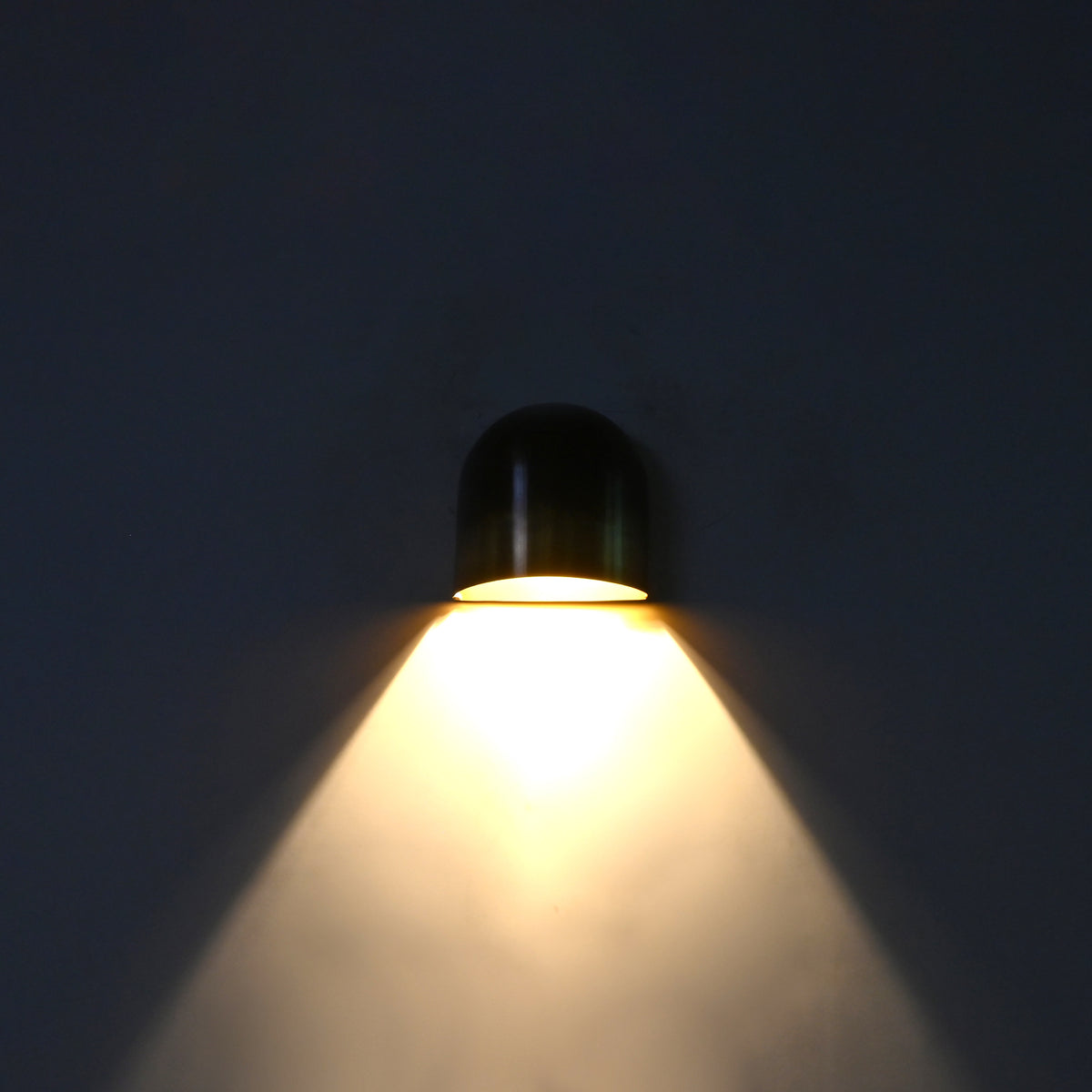 Closeup of dual tone brass wall sconce showing dark aged upper patina and warmer brass lower section