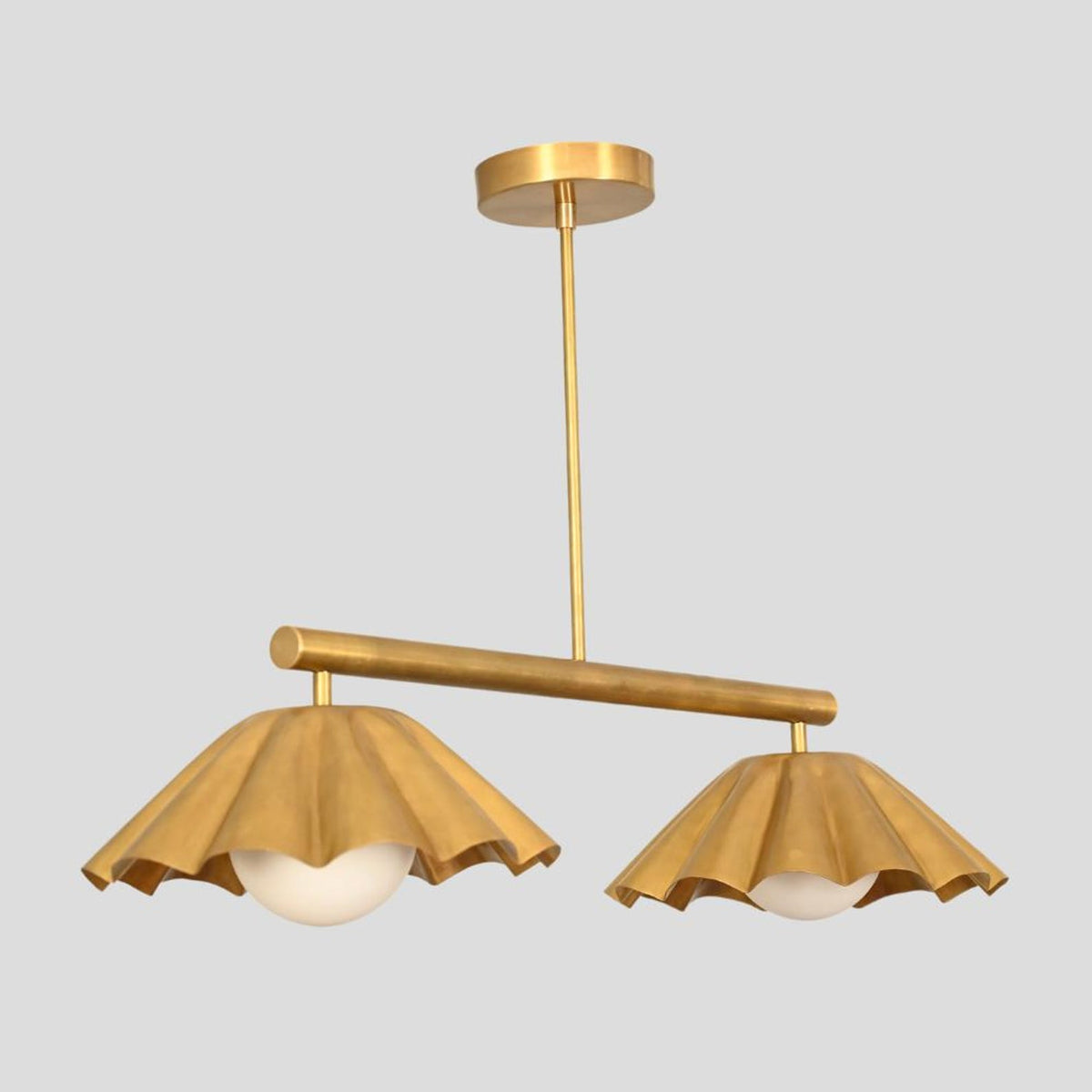 Elegant double-light brass chandelier with decorative ruffle shades, blending modern art with ambient lighting.