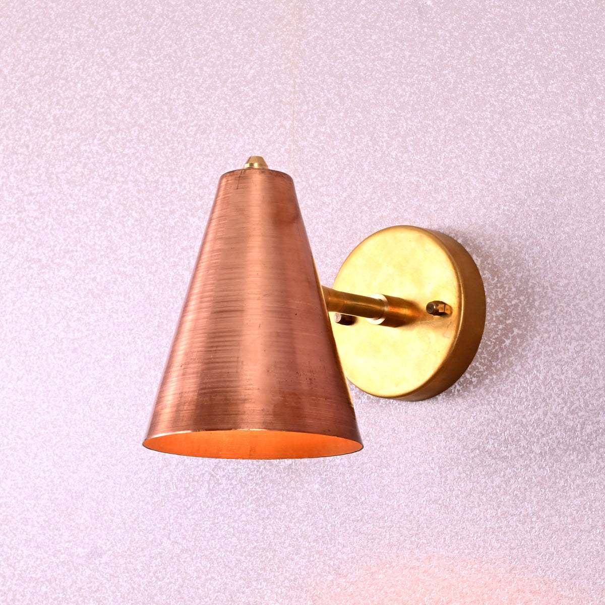 Elegant brass wall-mounted lamp with handcrafted conical copper shade, modern industrial style.