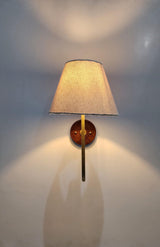 Elegant handmade brass wall sconce with linen fabric shade and soft warm light for bedroom or living space.