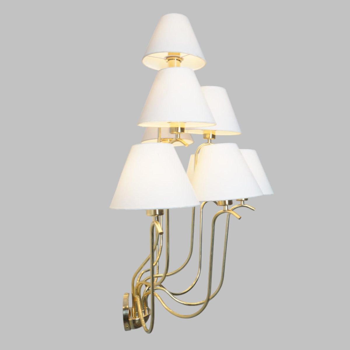 Angled view of luxurious brass wall sconce with soft white lampshades providing warm ambient illumination.