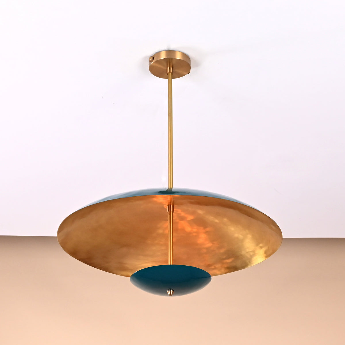 Side angle of emerald green and brushed brass pendant light featuring smooth lacquered finish and sculptural bowl design