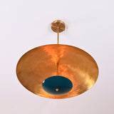 Upward perspective of handcrafted emerald green brass chandelier with warm reflective golden underside