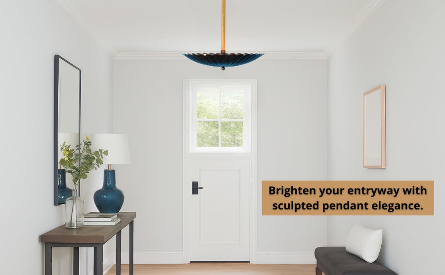 Sculptural floral pendant light casting a warm glow on the ceiling with raw brass rod and blackened brass shade.