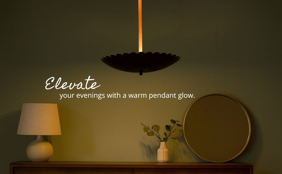 Dark green accent wall with mirror and dresser lit by a glowing floral brass pendant light in a cozy evening setting.