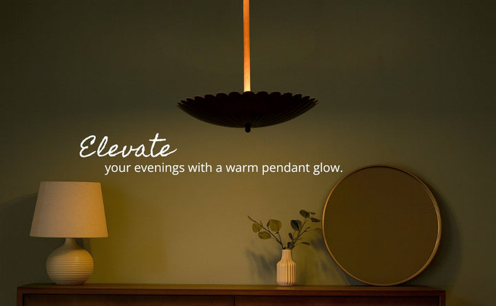 Dark green accent wall with mirror and dresser lit by a glowing floral brass pendant light in a cozy evening setting.