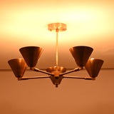 Bottom view of five-light brass cone chandelier highlighting warm indirect lighting and symmetrical arm layout.