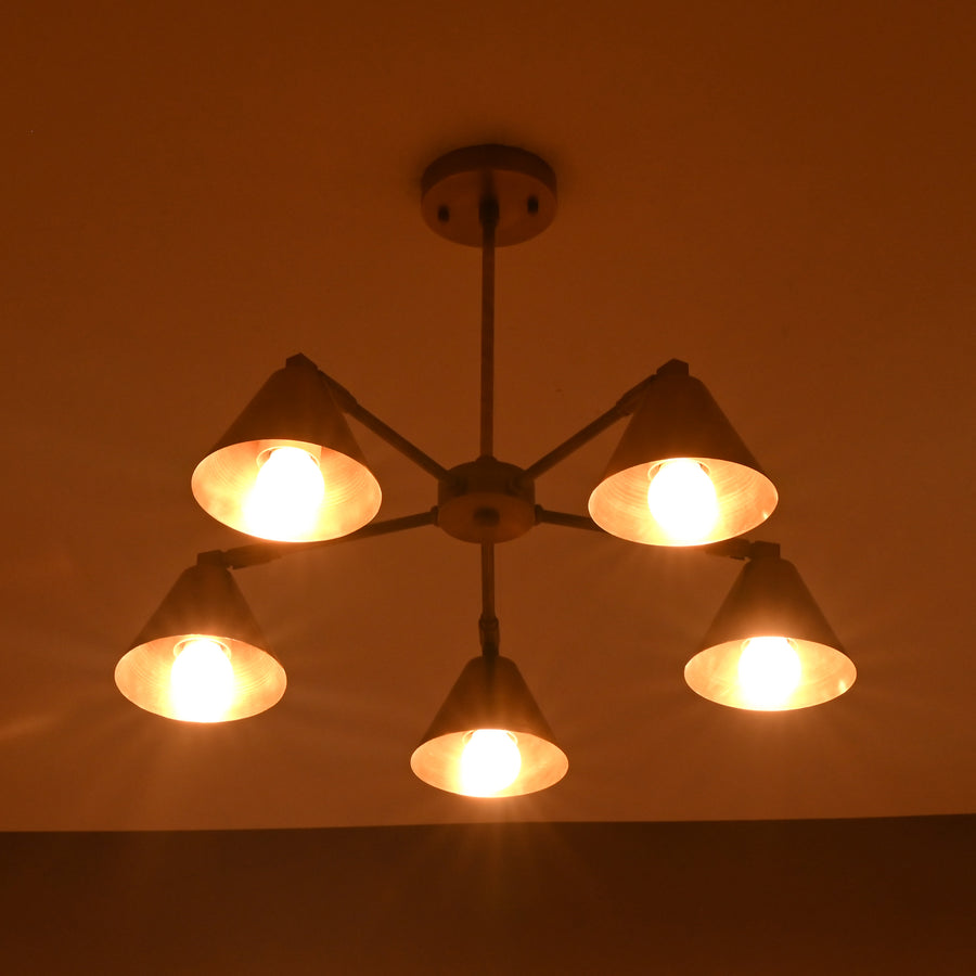 Five-light brushed brass cone chandelier with minimalist industrial design and warm ambient glow by Brass Leaf Studio.