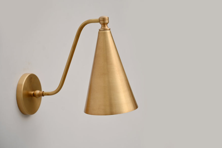 Handmade fixed-arm brass cone wall light with brushed satin finish, designed for modern and minimalist interiors