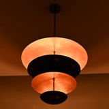 Close-up of chandelier’s copper interior and black brass exterior with indirect lighting glow