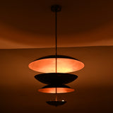 Chandelier glowing warmly in dark room, copper patina interior creating ambient uplighting