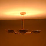 Four-bowl brass chandelier photographed in low lighting, showing deep golden glow and atmospheric ceiling illumination.
