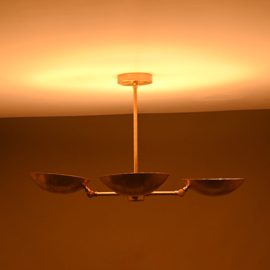 Front angle view of handcrafted solid brass chandelier with four hammered bowl shades and central brass rod suspension.
