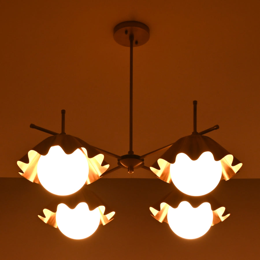 Four-light brushed brass chandelier with sculpted bowl shades and warm ambient lighting.