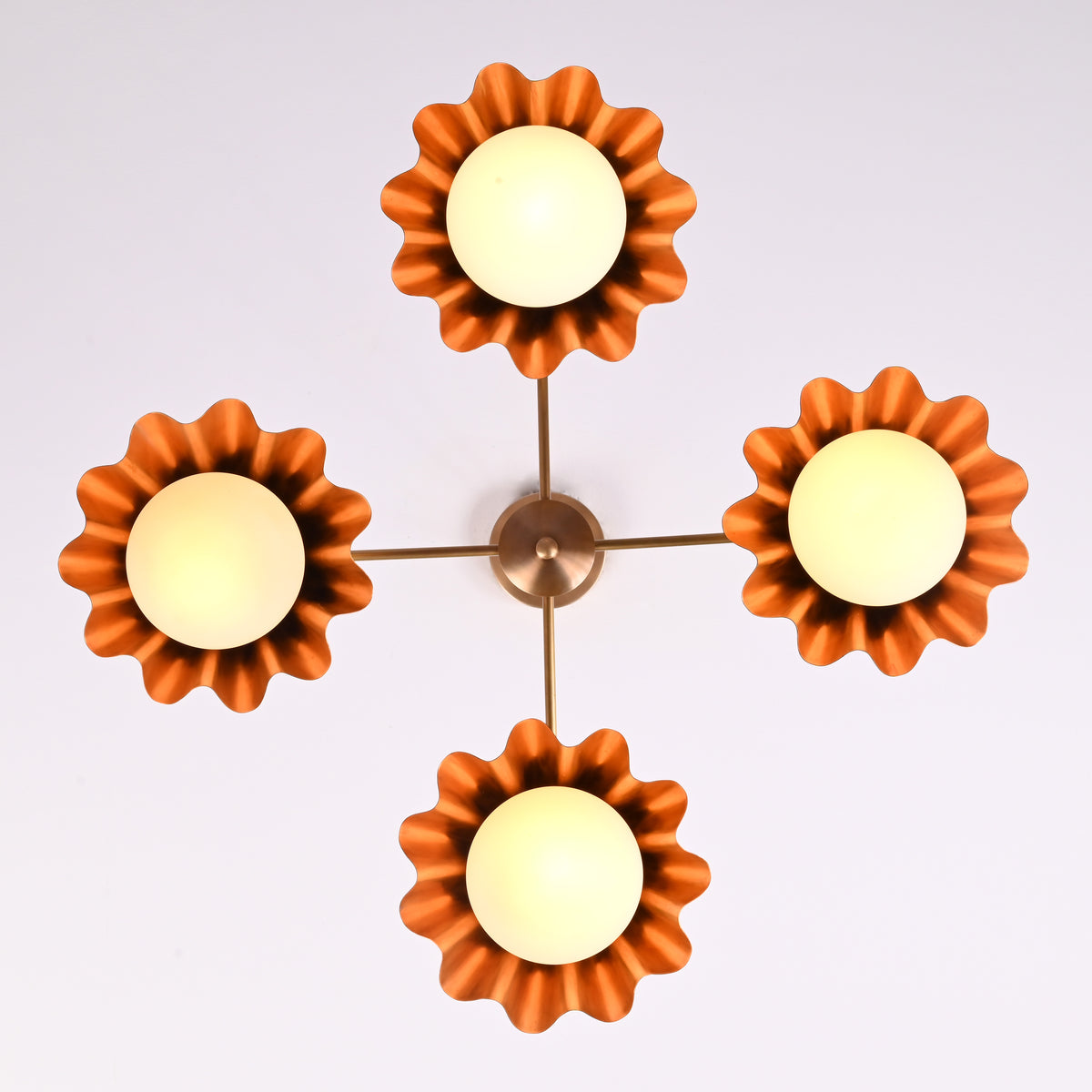Top view of four-light brushed brass chandelier with scalloped bowl shades and warm diffused glow.
