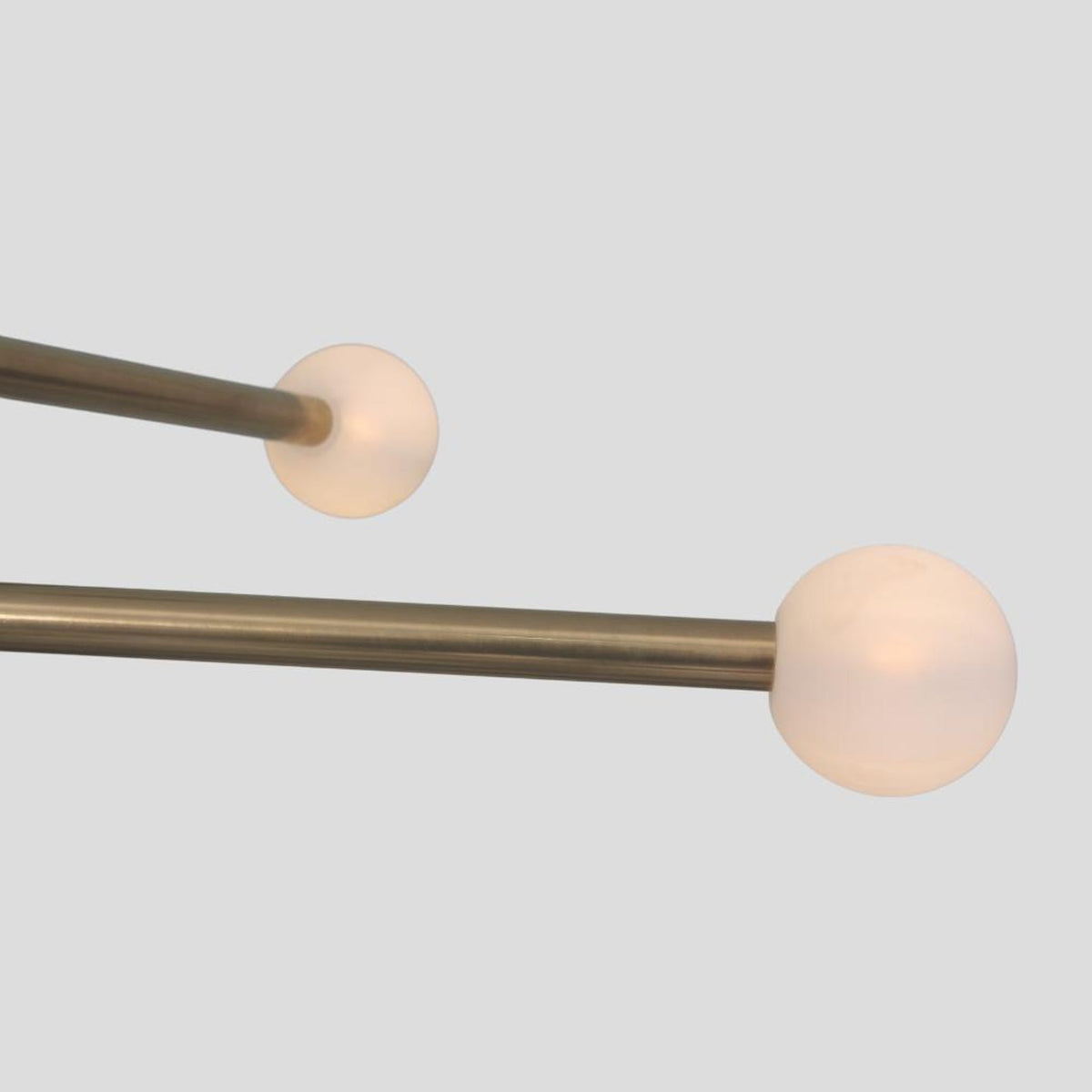 Close-up of frosted glass globe on brass chandelier rod, modern handmade lighting detail.