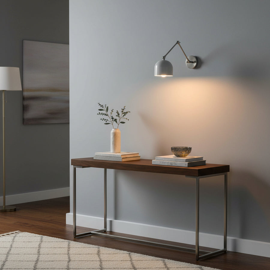 Full brass articulating wall sconce closeup showing jointed arm, round backplate, white dome shade, and warm downward light