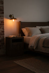 Full brass scalloped wall light shown illuminated with brass patina finish and warm ambient lighting