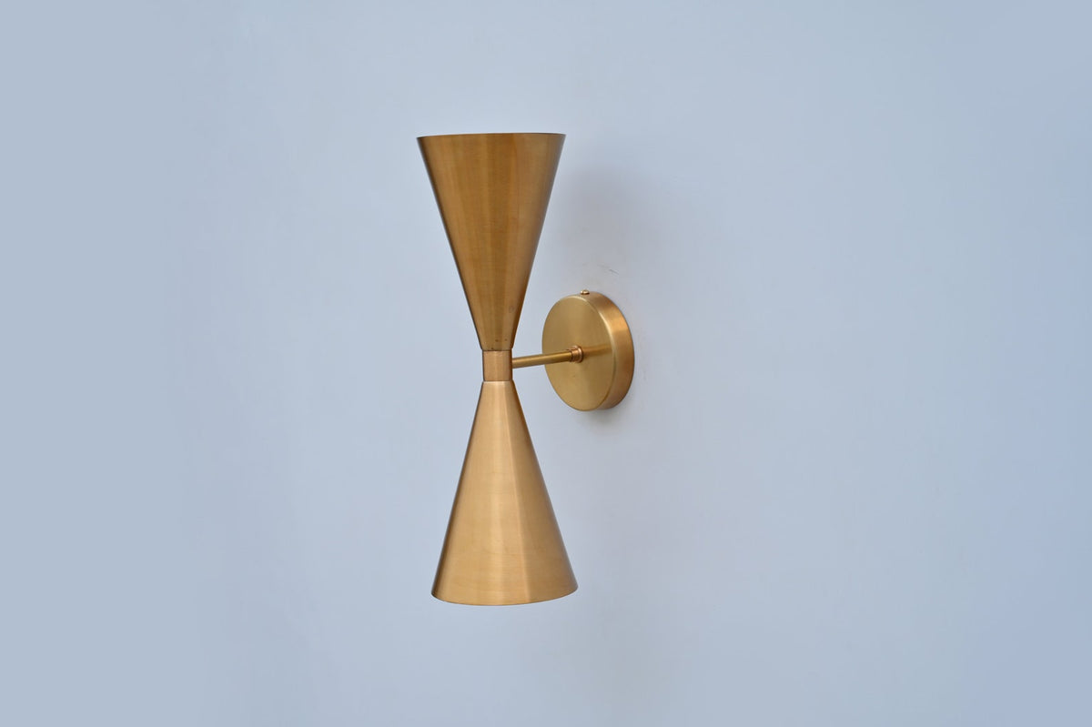 Geometric wall light featuring double cone brass design with clean lines, ideal for hallways, bedrooms, and boutique spaces.